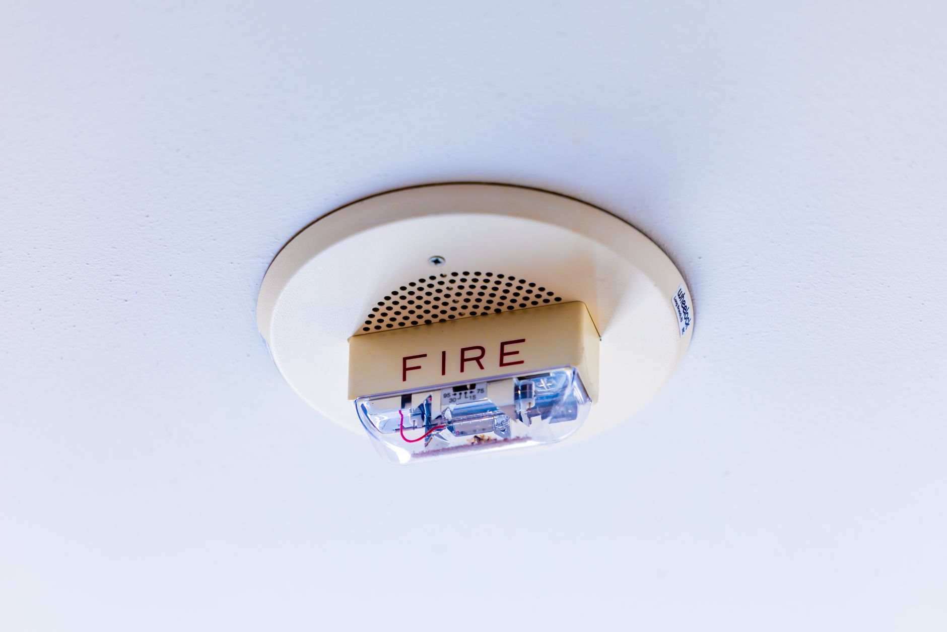 Fire alarm systems houston tx technician installing a smoke detector on a commercial ceiling